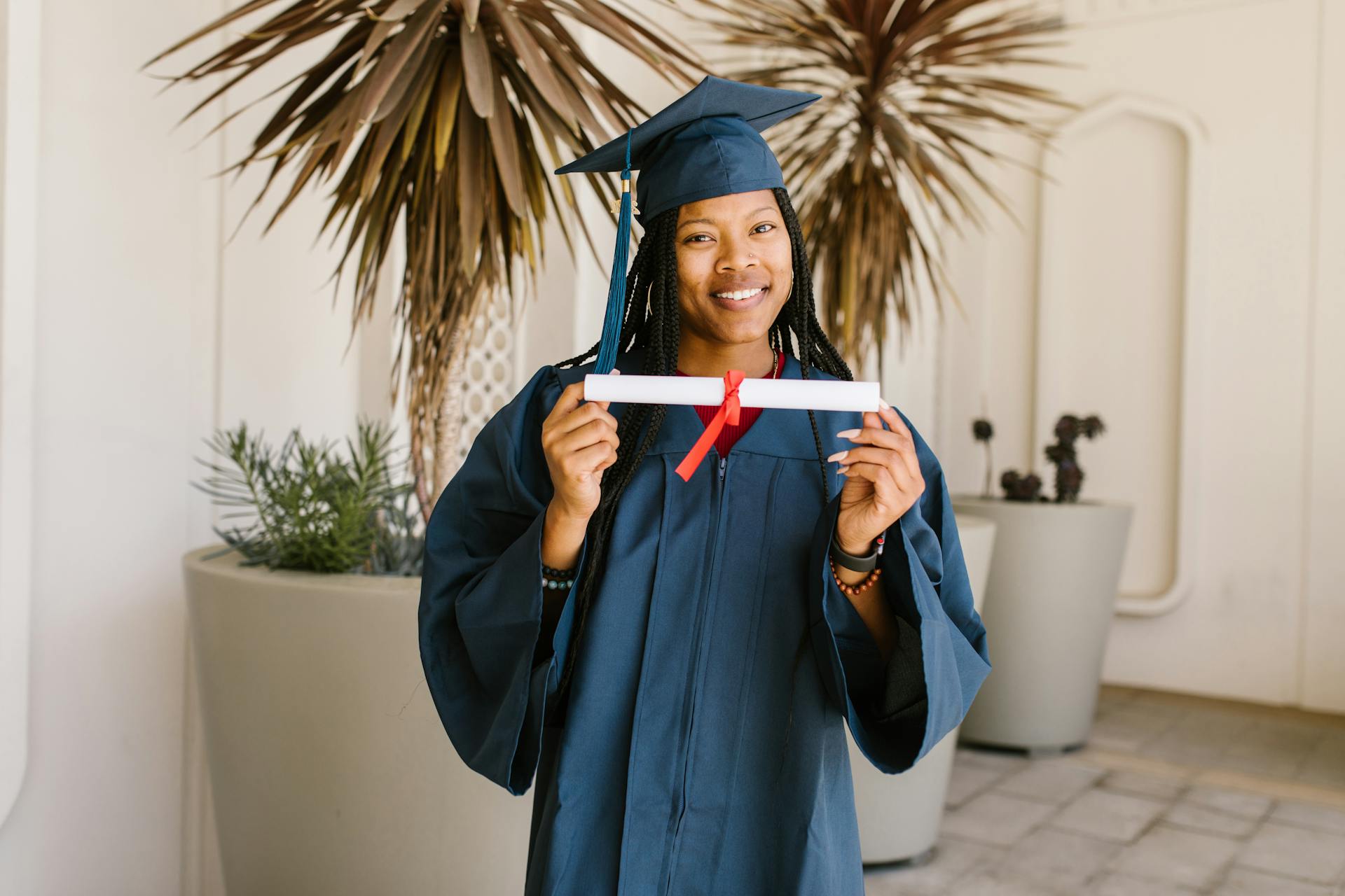 A Woman in Academic Dress Showing the Certificate she is Holding while Smiling at the Camera