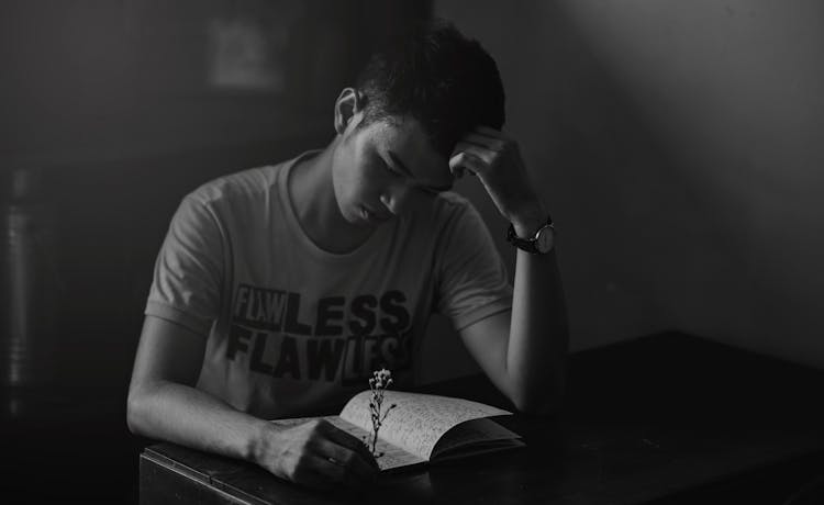 Grayscale Photography Of Man In Shirt Reading Notebook