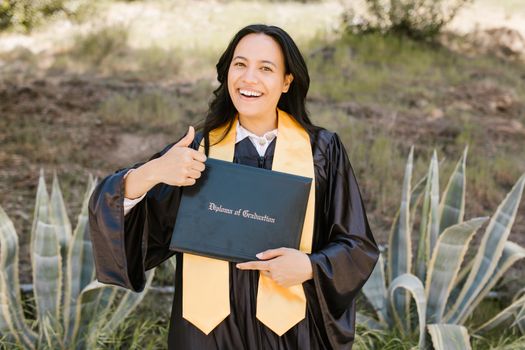 Joyful female graduate holding her diploma in an outdoor celebration.