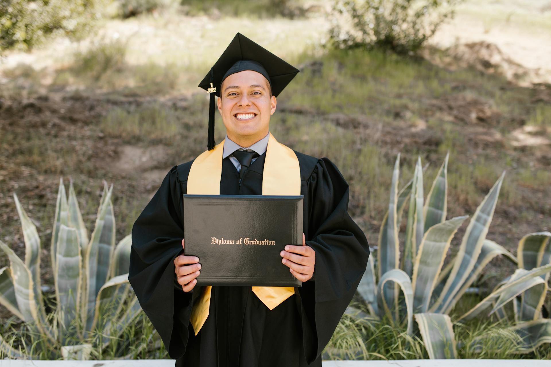 Proud Smiling Man in a Graduate Cap Holding Up his Diploma