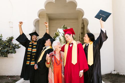 Free Happy graduates celebrating their achievement outdoors with a smiling elderly woman. Stock Photo