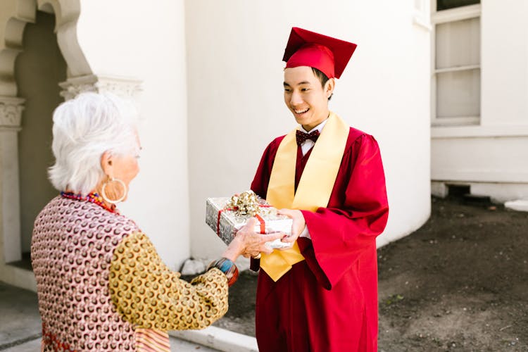 Grandma Handing A Congratulation Gift To Grandson