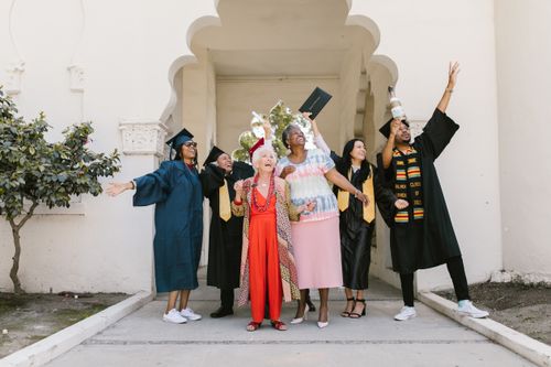 Free Graduates and family celebrating outdoors, expressing joy and success. Stock Photo