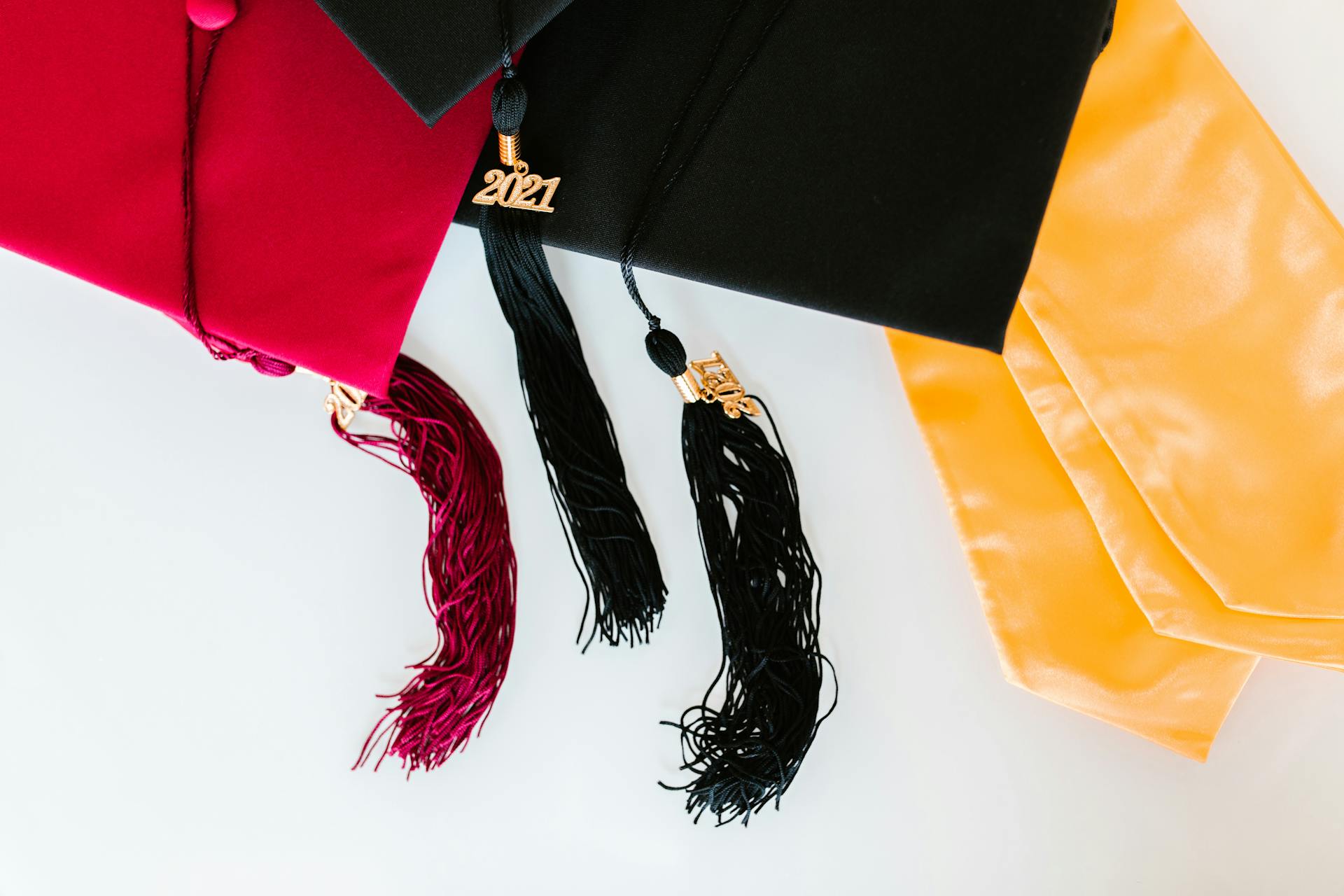 Close-up of graduation caps with 2021 tassels and colorful stoles.
