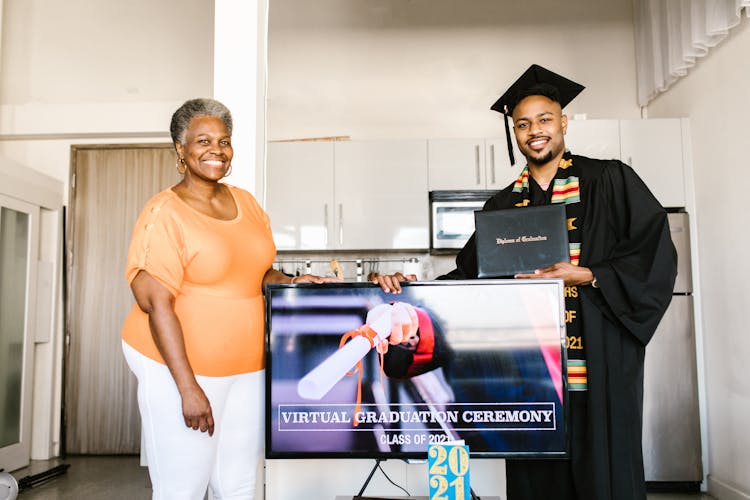 Man Wearing Graduation Toga Having Picture Taken Together With His Mother 