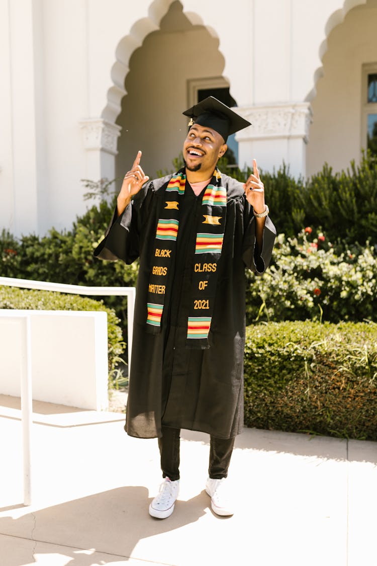 Man Pointing His Fingers Up While Wearing Graduation Gown 