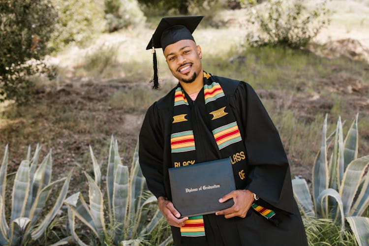 Student Smiling While Holding His Diploma 