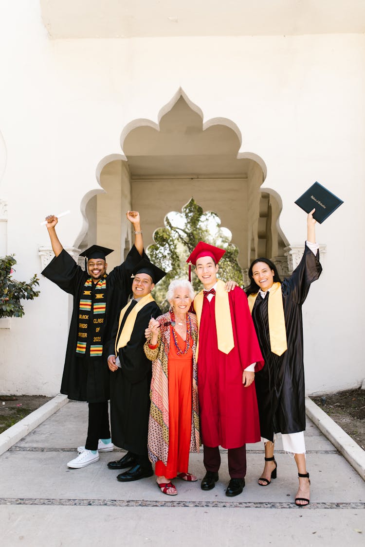 Newly Graduate Students Posing With Their Hands Raised 