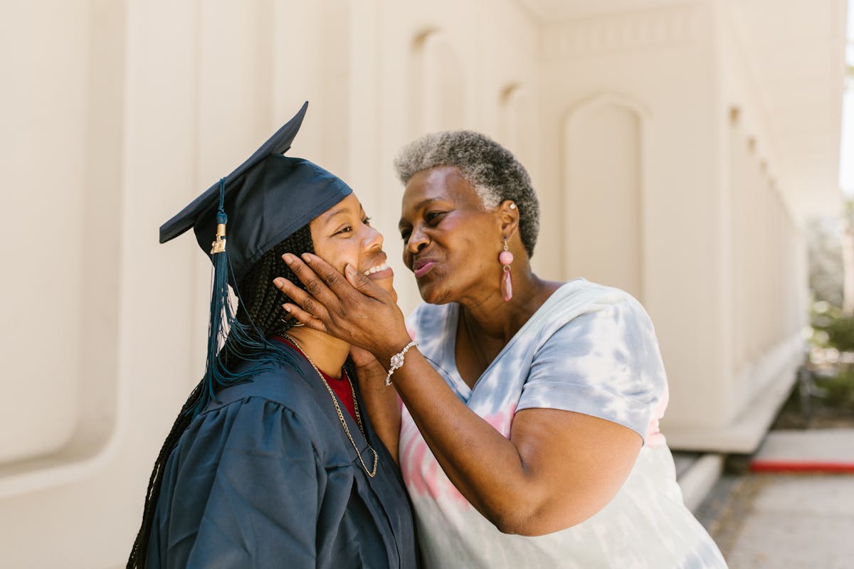 Grandmother kissing graduating daughter