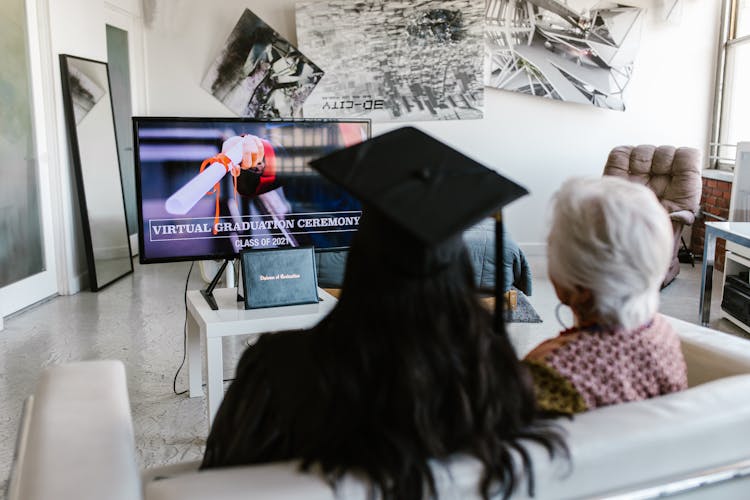 A Person Wearing Graduation Cap  Attending Virtual Graduation Ceremony With An Elderly