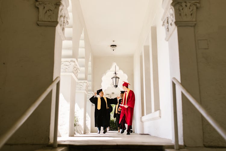 Men Walking Wearing Their Graduation Gowns