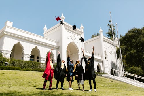 Free People Wearing Graduation Gowns Tossing their Graduation Caps in the Air Stock Photo