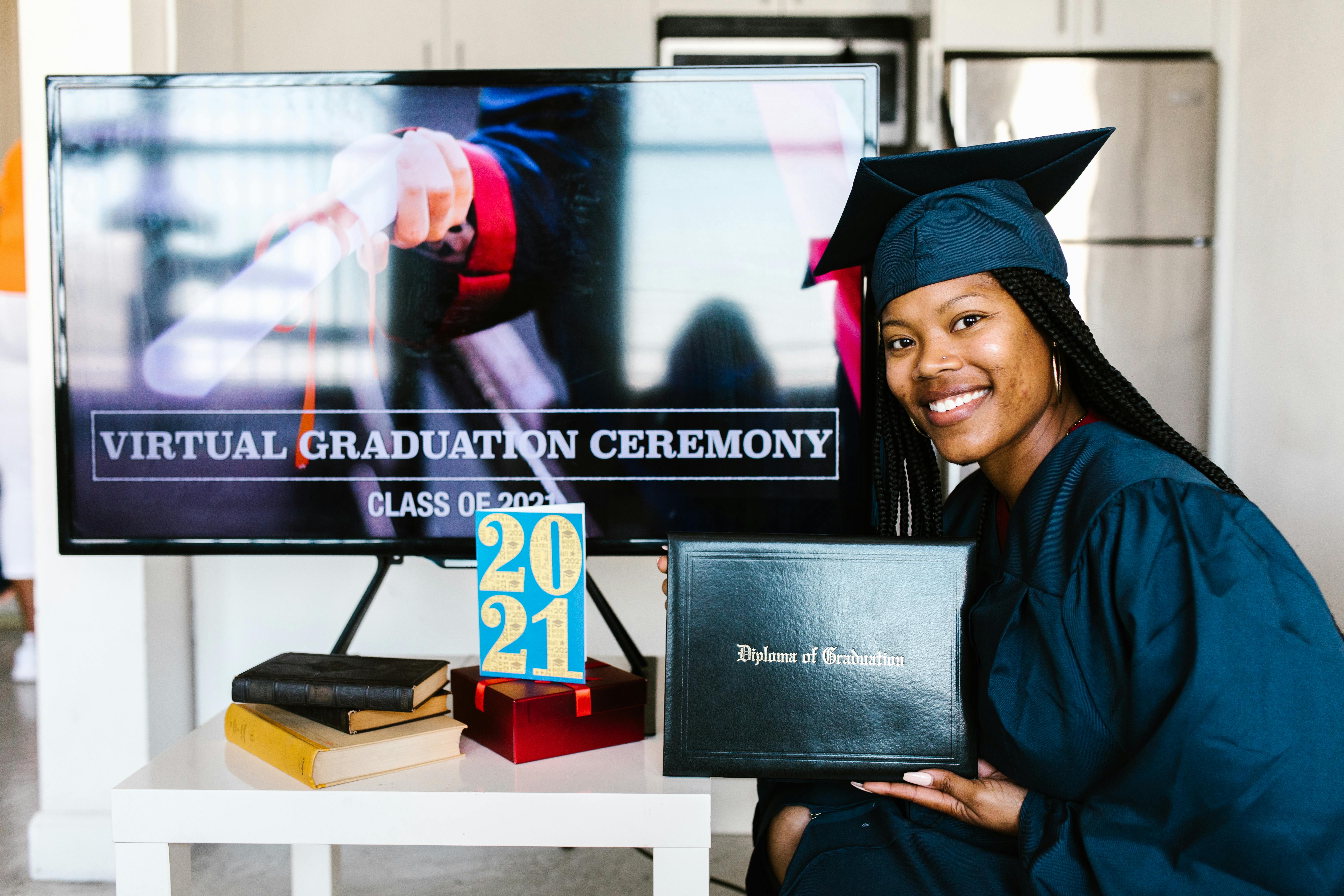 woman sitting near the flat screen television while holding her diploma