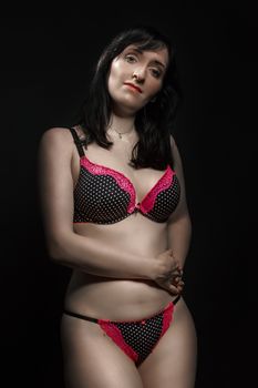 Stylish portrait of a woman in elegant polka dot lingerie on a dark background.