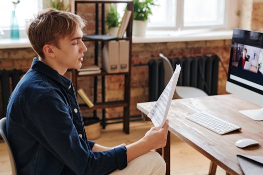 A young man attentively participating in a video call from his home office.