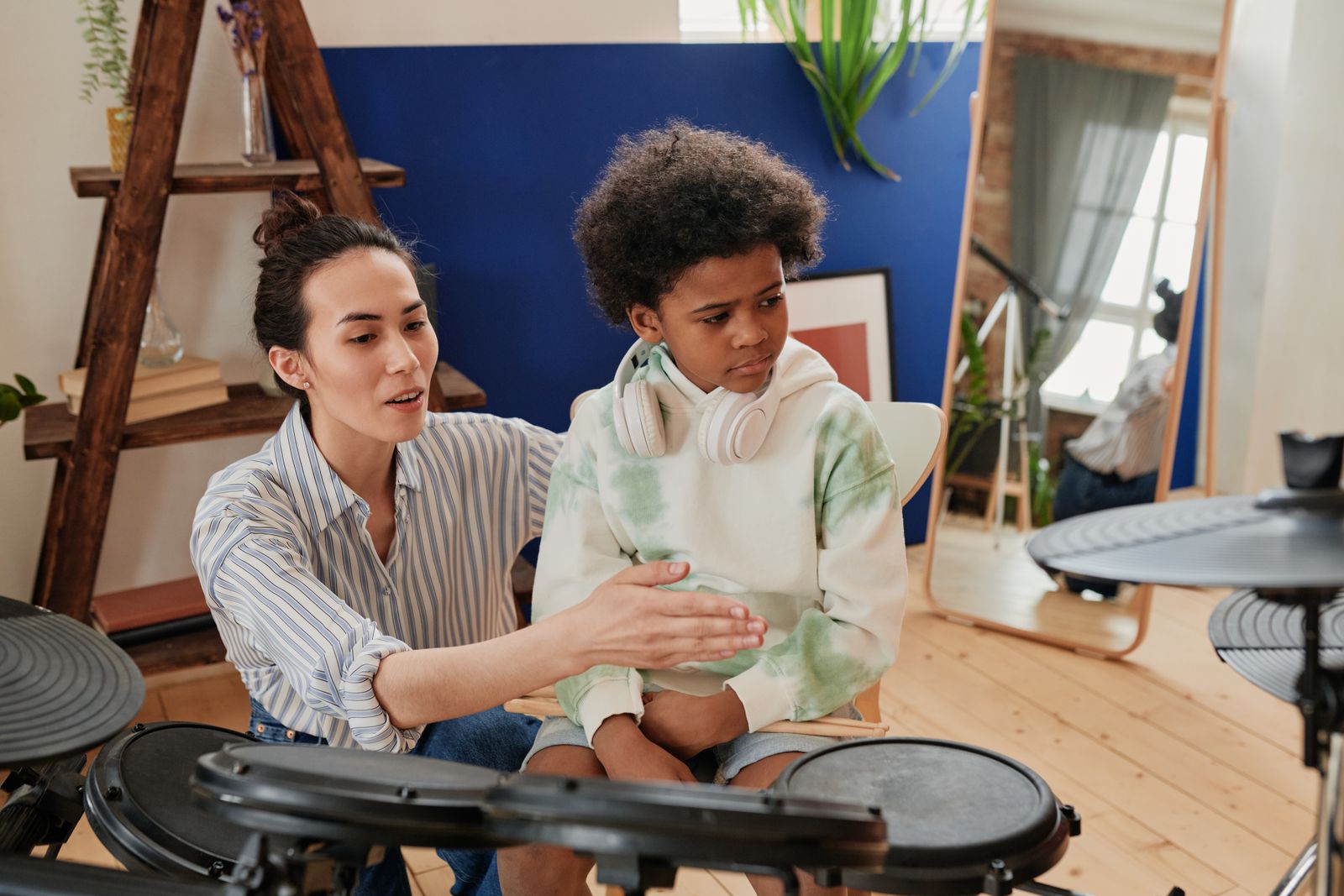Teacher guiding a child at electronic drums — the in-person correction a video cannot provide