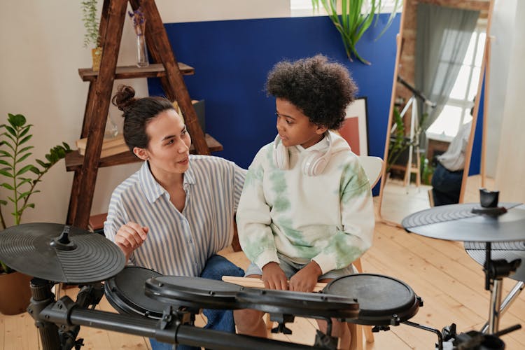 A Woman Teaching A Boy How To Drum