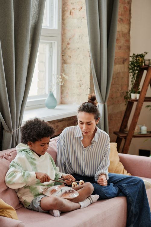 Free A boy receives music lessons from an adult on a cozy living room sofa. Stock Photo