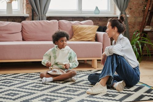 Free A child playing a steel drum while sitting indoors with a mentor nearby. Stock Photo