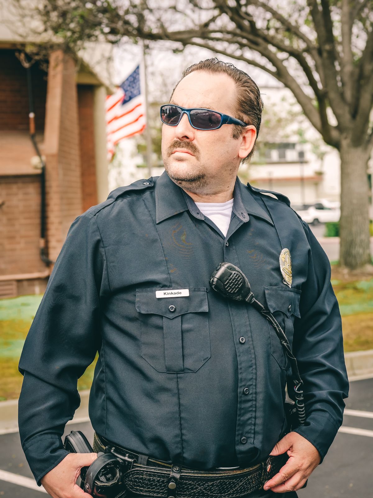 US law enforcement officer in uniform facing the camera near an American flag — federal law enforcement mortgage programs from a lender who understands law enforcement