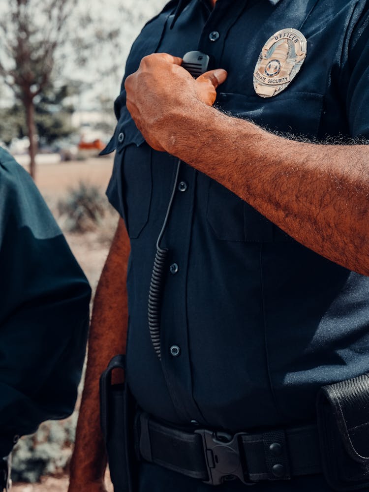 A Policeman In Uniform Holding A Radio