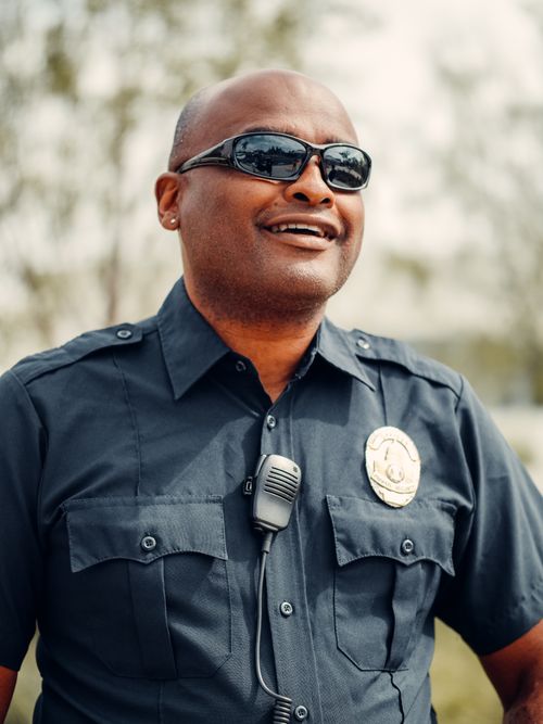 Free Close-up of a smiling African American police officer in uniform with sunglasses outdoors. Stock Photo