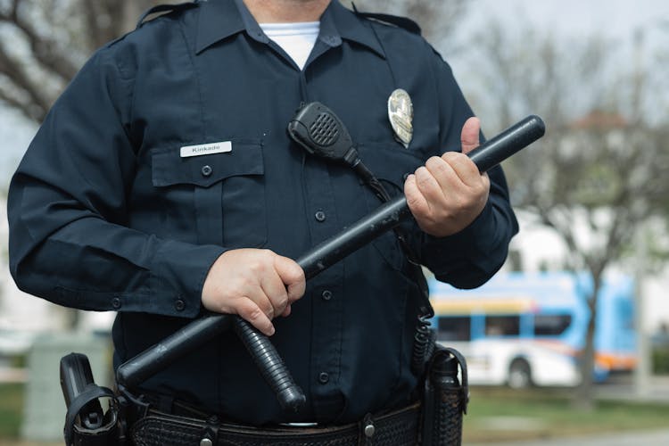 Man In Black Police Uniform Holding A Baton