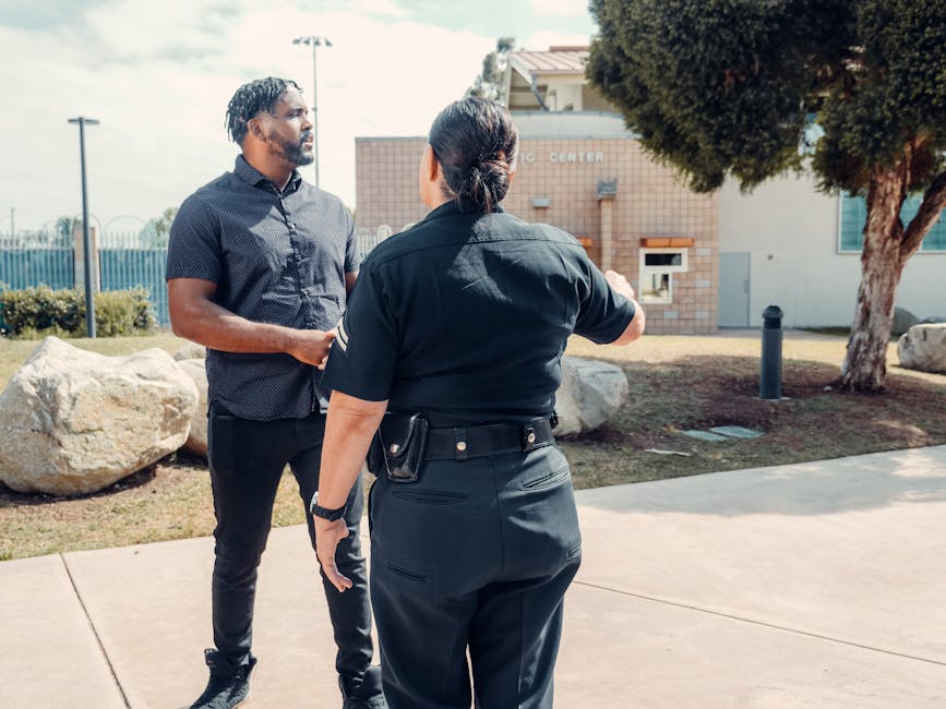 A police officer talks to a man outdoors near a community center.