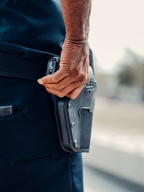 Photo by Kindel Media A police officer's hand gripping the holster of a handgun, symbolizing readiness and security.