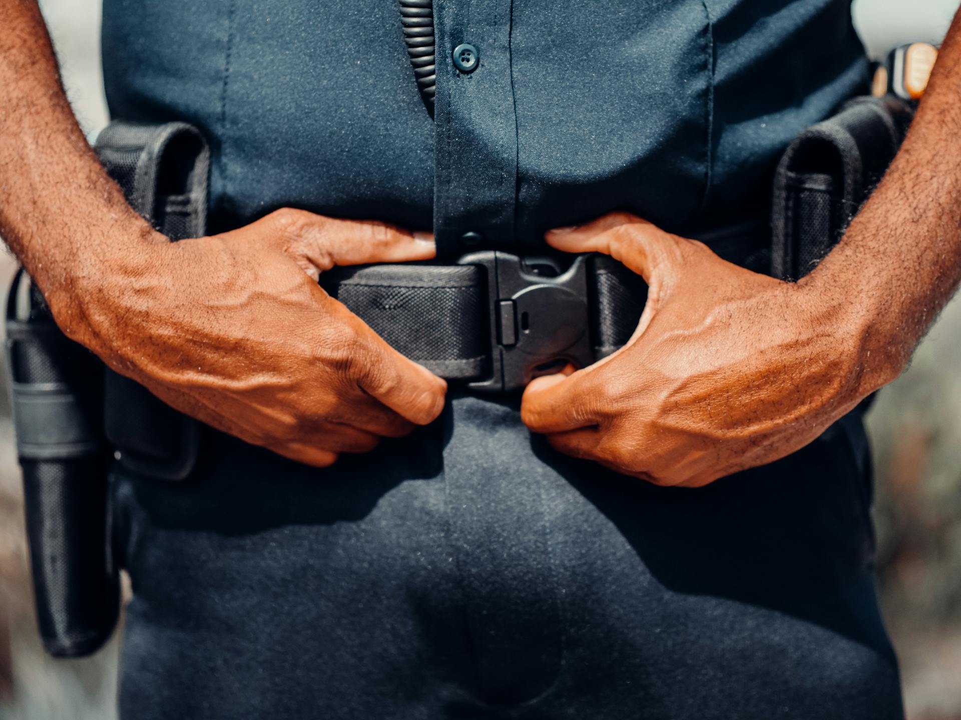 A Police Officer In Blue Uniform Holding a Black Belt