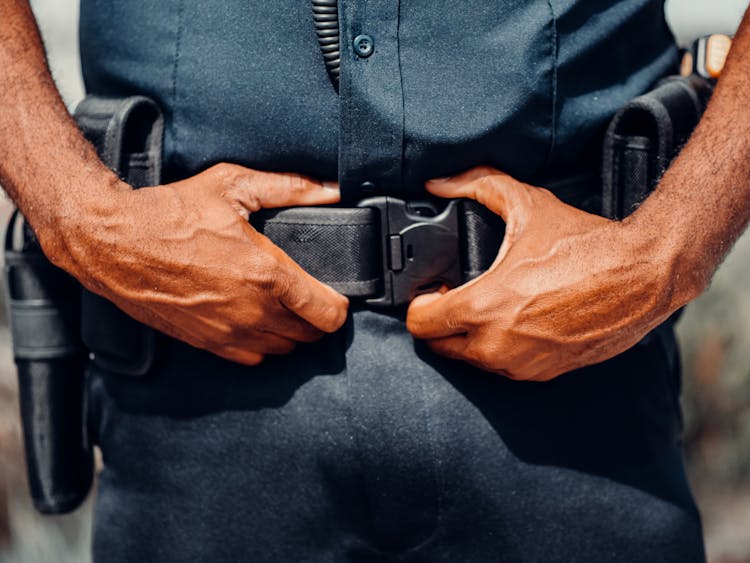 A Police Officer In Blue Uniform Holding A Black Belt