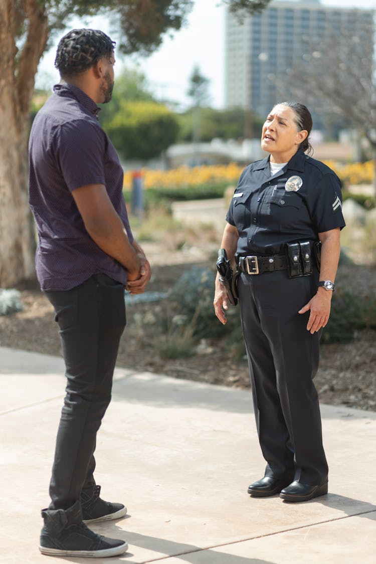 A Policewoman Talking To A Man In Blue Polo Shirt On The Street