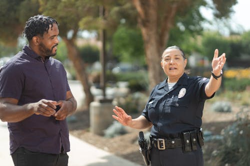 Free Man in Black Button Up Shirt Talking to a Policewoman Stock Photo