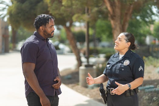 A police officer engaging warmly with a community member outdoors on a sunny day.