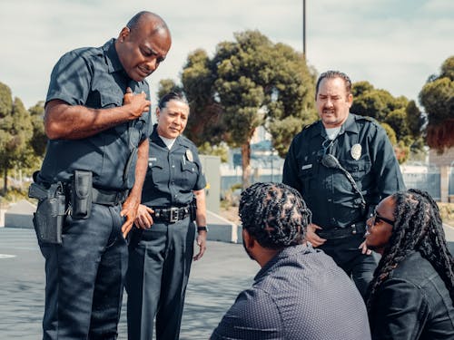 Free Police Officers Talking to Two Men on the Street Stock Photo