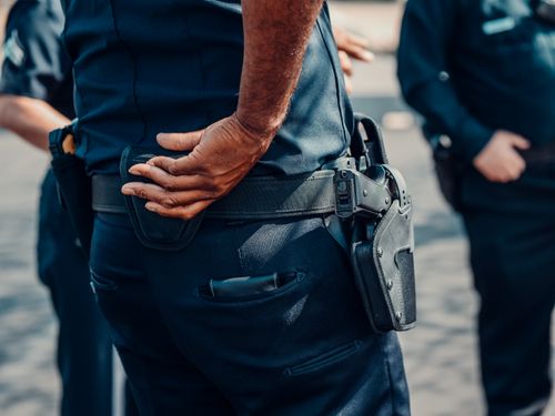 Free Close-up view of a police officer in uniform with a focus on the holster and handgun. Stock Photo