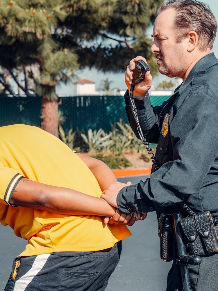 Police Officer Arresting A Man In Yellow Shirt