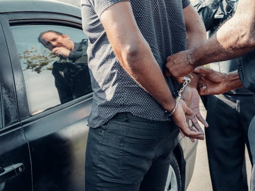 Person with Handcuffs Standing Near the Car 