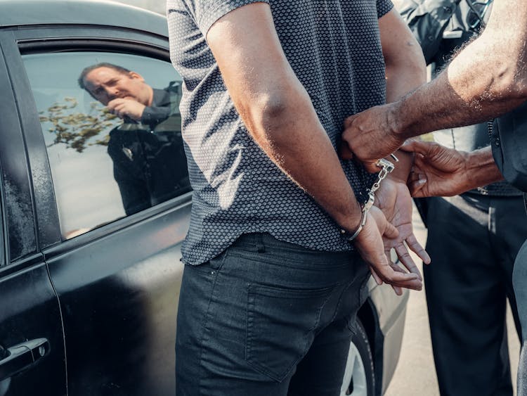 Person With Handcuffs Standing Near The Car 