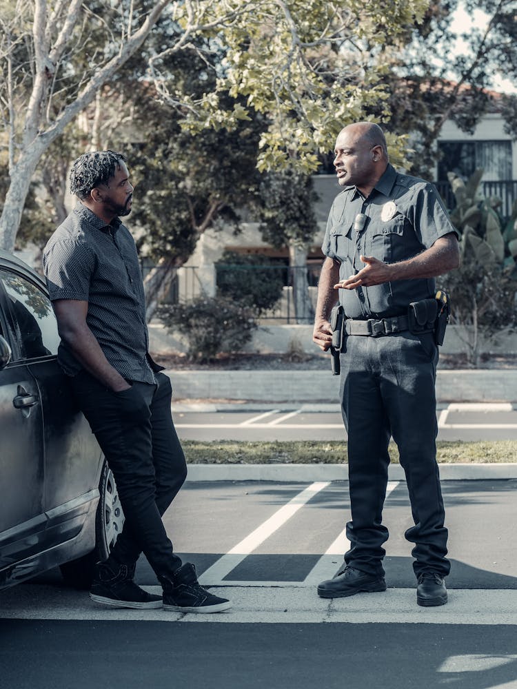 Police Officer Talking To The Man Leaning On The Car 