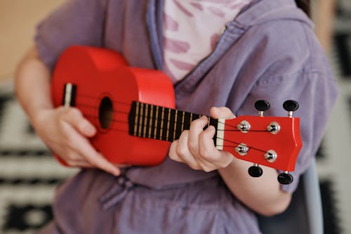 A Person Playing a Red Ukulele