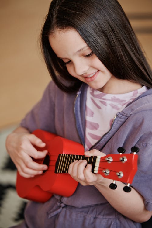 Free Young Girl Playing a Stringed Instrument Stock Photo