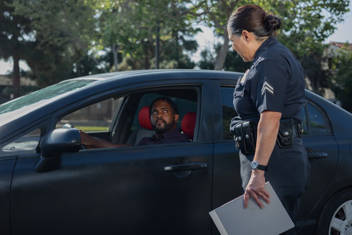 A policewoman discusses a traffic violation with a driver on a sunny day