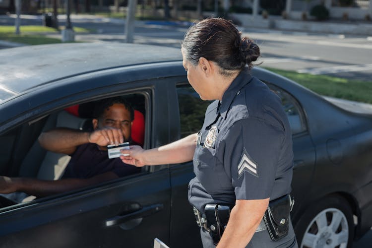 Man Giving His Driver's License To The Policewoman 