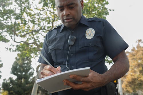 Free Man in Black Police Uniform Writing on White Book Stock Photo