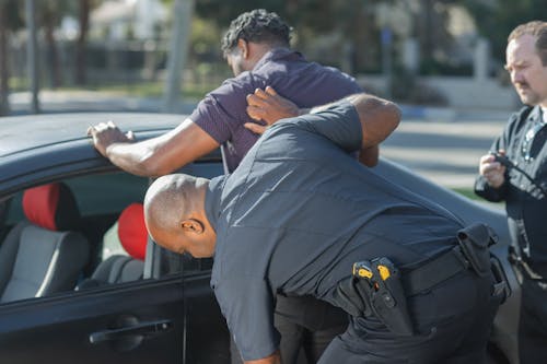 Free Man in Gray T-shirt Being Searched by Two Police Officers Stock Photo