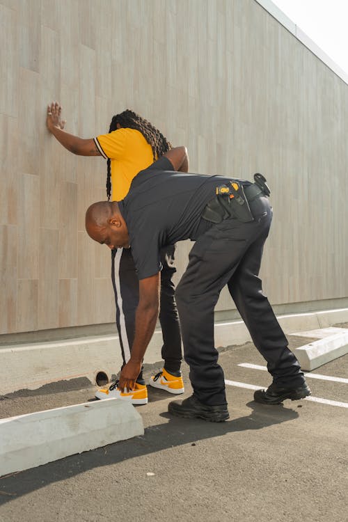 Free Man in Yellow Shirt Being Searched by a Policeman Stock Photo