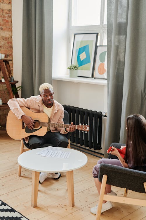 Photo of a Man in Black Pants Playing an Acoustic Guitar