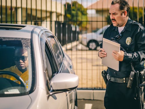 Free Police Officer Talking to the Driver of the Silver Car Stock Photo