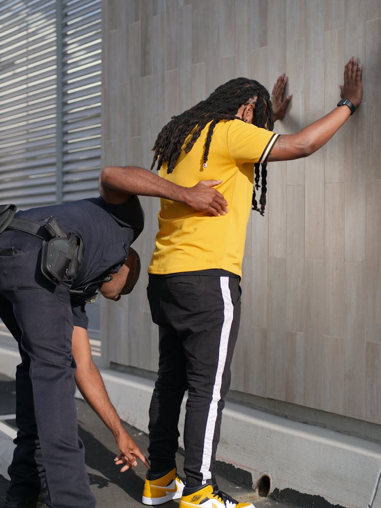 Policeman Frisking The Person In Yellow Shirt 